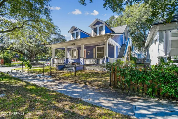 a view of a white house with a large pool plants and large trees