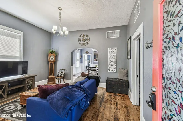 a living room with furniture piano and a chandelier