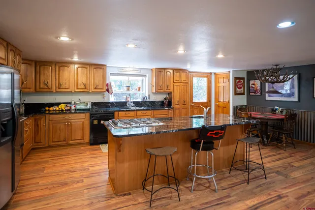 a kitchen with stainless steel appliances granite countertop wooden floors stove top oven with a dining table and chairs