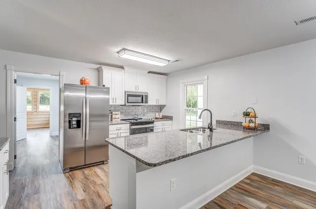 a kitchen with stainless steel appliances granite countertop a sink refrigerator and cabinets