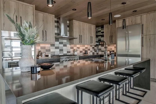 a kitchen with stainless steel appliances granite countertop a table chairs in it and wooden floors
