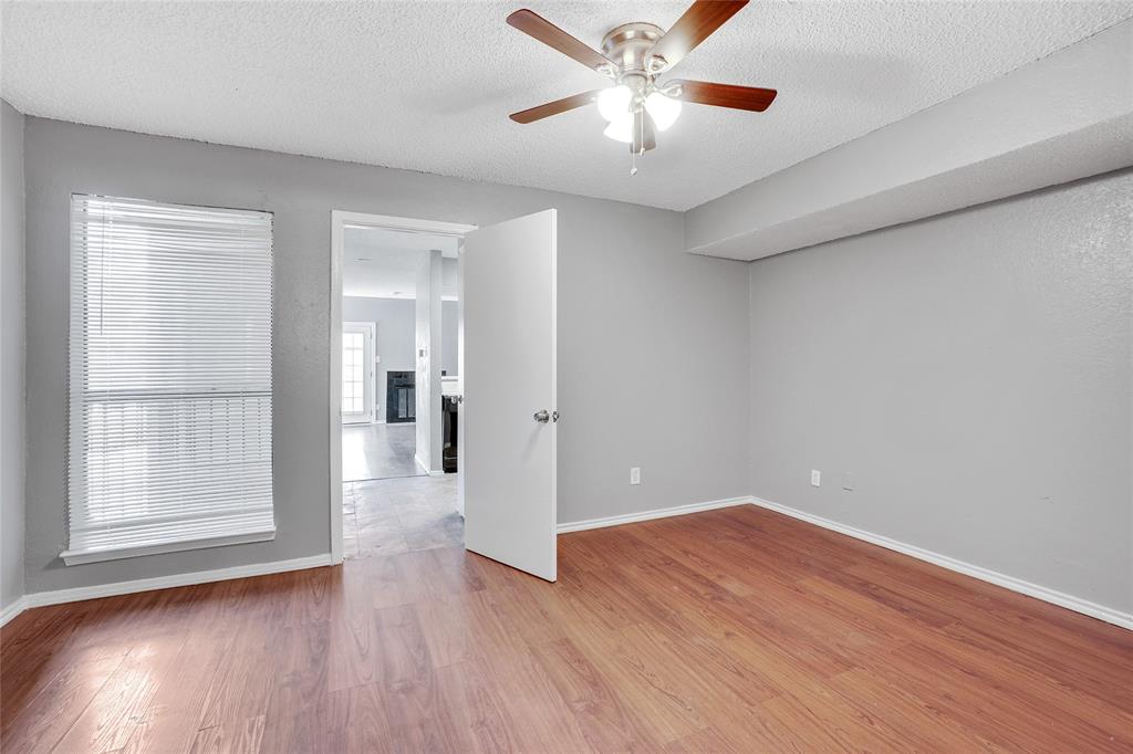 9815 Walnut Street, Unit 214 Dallas, TX 75243 - Photo 22 of 29 an empty room with wooden floor chandelier fan and windows