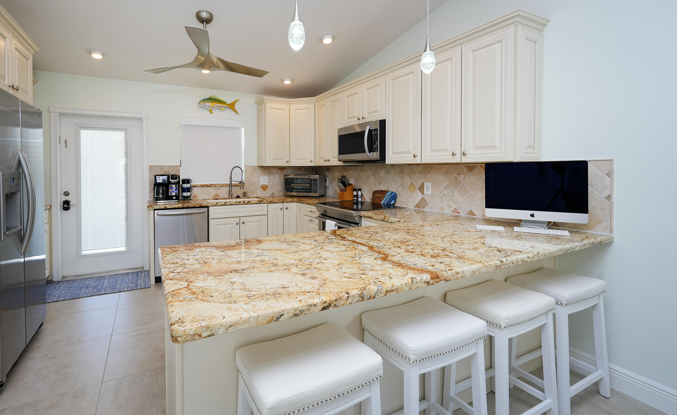 610 9th Street Key Colony Beach, FL 33051 - Photo 10 of 28 a kitchen with stainless steel appliances granite countertop a table chairs sink and cabinets