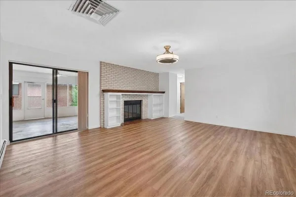 a view of an empty room with wooden floor and a fireplace