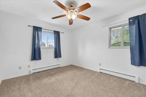 an empty room with windows and fan