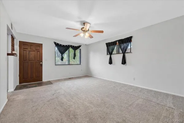 an empty room with windows and ceiling fan