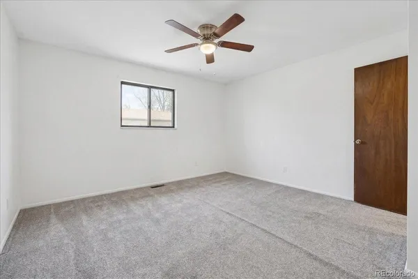 an empty room with closet and a chandelier fan