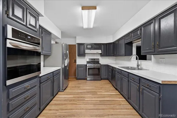 a large kitchen with stainless steel appliances wooden cabinets a stove and a microwave