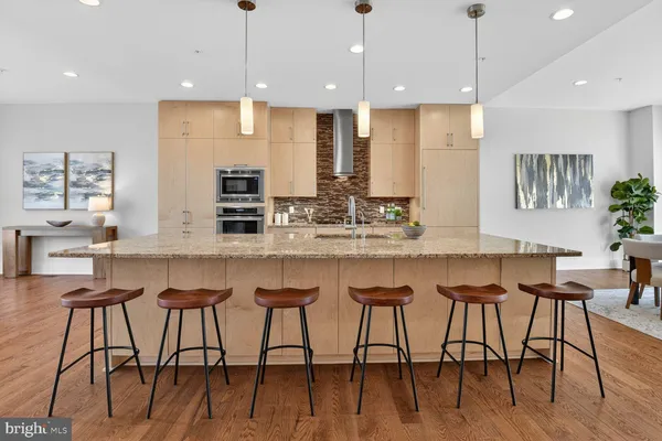 a kitchen with stainless steel appliances granite countertop a kitchen island and chairs in it