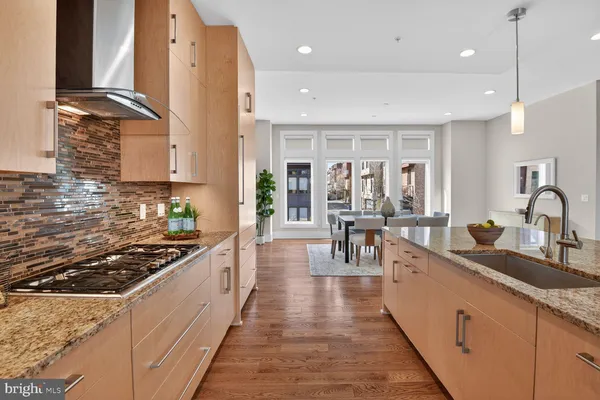 a large kitchen with stainless steel appliances granite countertop a lot of counter space and wooden floors