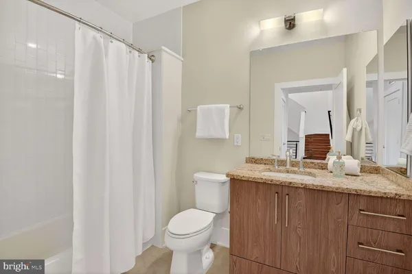 a bathroom with a granite countertop sink toilet and mirror