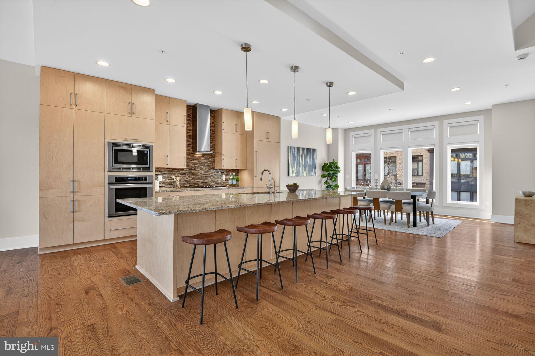 5320 Merriam Street Bethesda, MD 20814 - Photo 10 of 51 a kitchen with stainless steel appliances granite countertop a stove top oven a sink a dining table and chairs with wooden floor