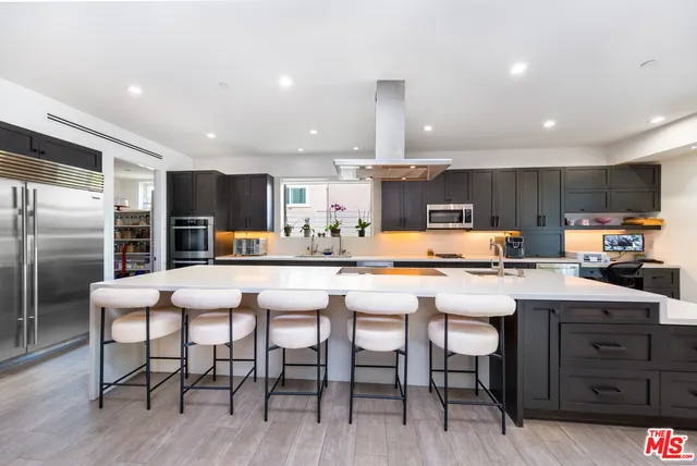 a kitchen with stainless steel appliances a table chairs refrigerator and microwave