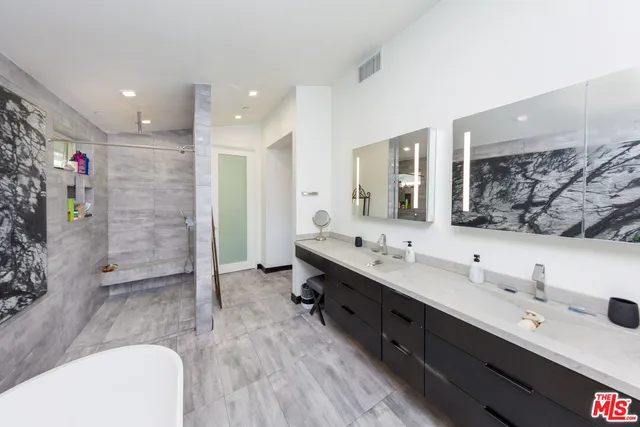 a bathroom with a double vanity sink a large mirror and shower
