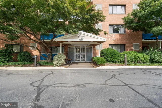 a front view of a house with a garden and trees