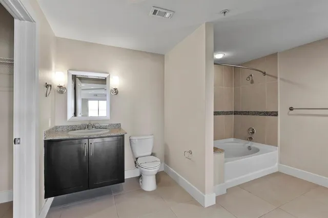 a bathroom with a granite countertop sink a toilet and shower