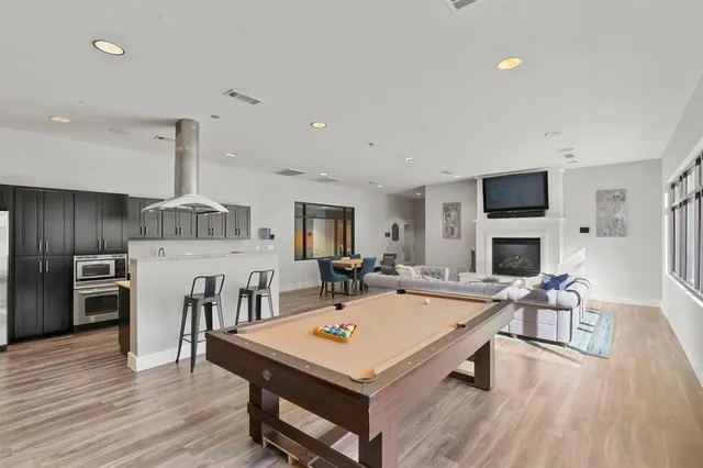 a living room with stainless steel appliances furniture a fireplace a flat screen tv and couches