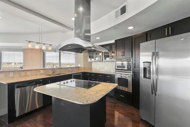 a kitchen with stainless steel appliances granite countertop a sink a refrigerator and wooden cabinets