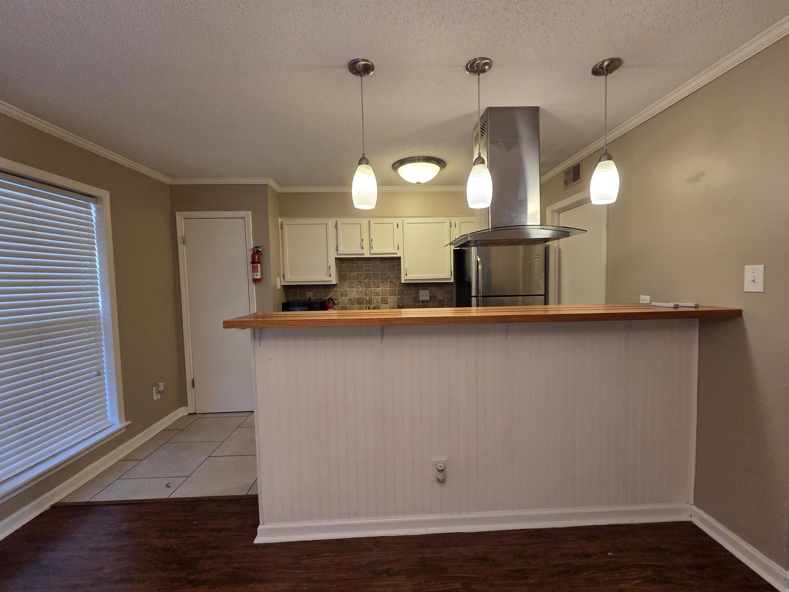 2104 Harbert Avenue Memphis, TN 38104 - Photo 15 of 26 Kitchen featuring tasteful backsplash, pendant lighting, a peninsula, island exhaust hood, and white cabinetry