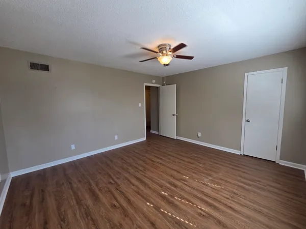 a view of an empty room with a window and wooden floor