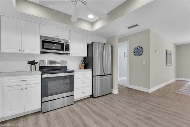 a kitchen with stainless steel appliances granite countertop a refrigerator stove a sink and a microwave oven with wooden floor