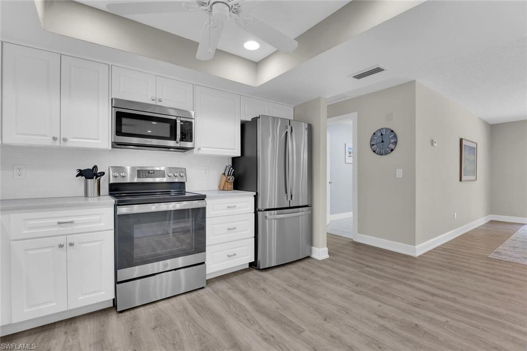 150 1st Avenue North Naples, FL 34102 - Photo 9 of 44 a kitchen with stainless steel appliances granite countertop a refrigerator stove a sink and a microwave oven with wooden floor