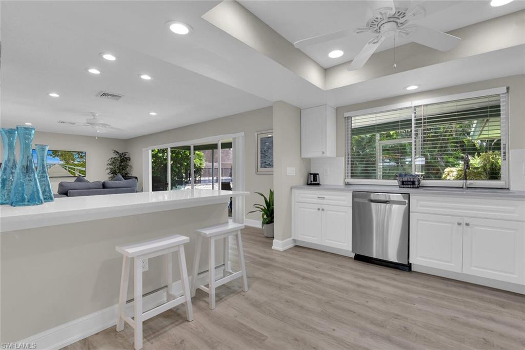 150 1st Avenue North Naples, FL 34102 - Photo 10 of 44 a kitchen with white cabinets and wooden floors