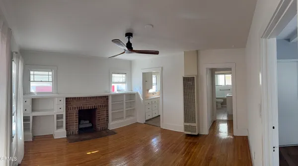 a view of empty room with wooden floor and a fireplace