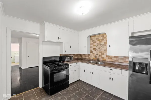 a kitchen with granite countertop a sink a stove and cabinets