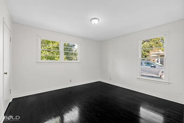 a view of an empty room with wooden floor and a window