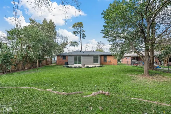 a view of a yard in front of a house with a large tree