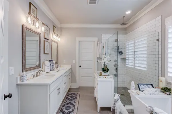 a bathroom with a double vanity sink a toilet a mirror and shower