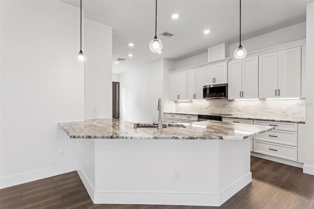17540 3rd Street Montverde, FL 34756 - Photo 15 of 80 a kitchen with stainless steel appliances granite countertop a sink a stove a refrigerator and island with wooden floor