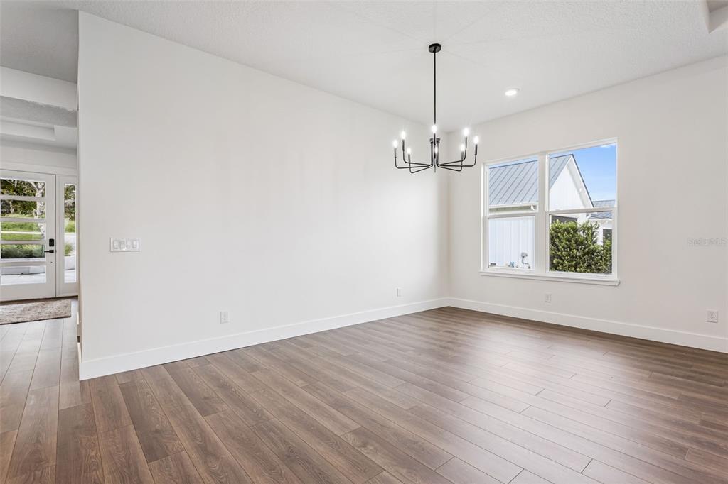 17540 3rd Street Montverde, FL 34756 - Photo 19 of 80 an empty room with wooden floor chandelier and windows