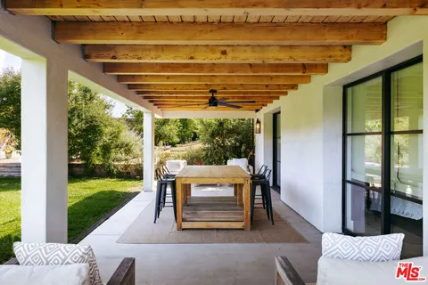a view of a backyard with lawn chairs under an umbrella