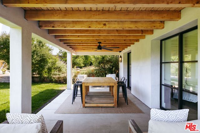 a view of a backyard with lawn chairs under an umbrella