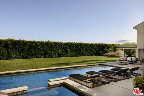 a view of a swimming pool with a lawn chairs under palm trees