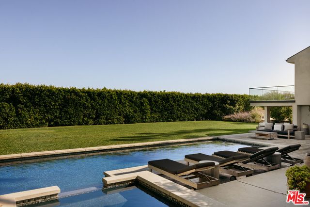 a view of a swimming pool with a lawn chairs under palm trees