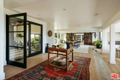 a living room with furniture large window and wooden floor