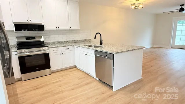 a kitchen with stainless steel appliances granite countertop a stove top oven a sink a microwave and a refrigerator