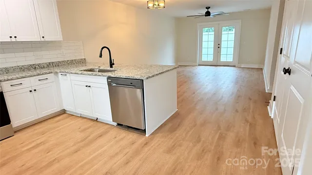 a kitchen with a sink wooden floor and white appliances