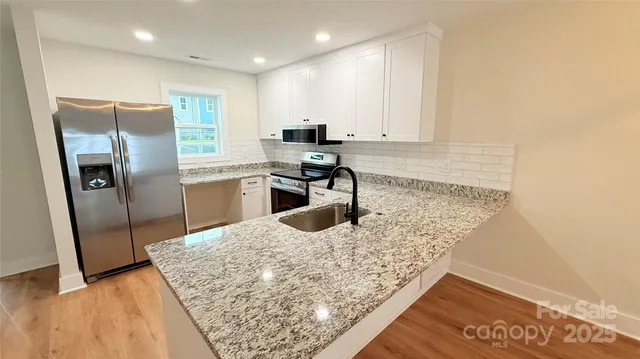 a kitchen with stainless steel appliances granite countertop a sink stove and refrigerator