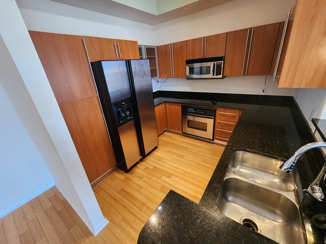 a view of kitchen with stainless steel appliances wooden floor
