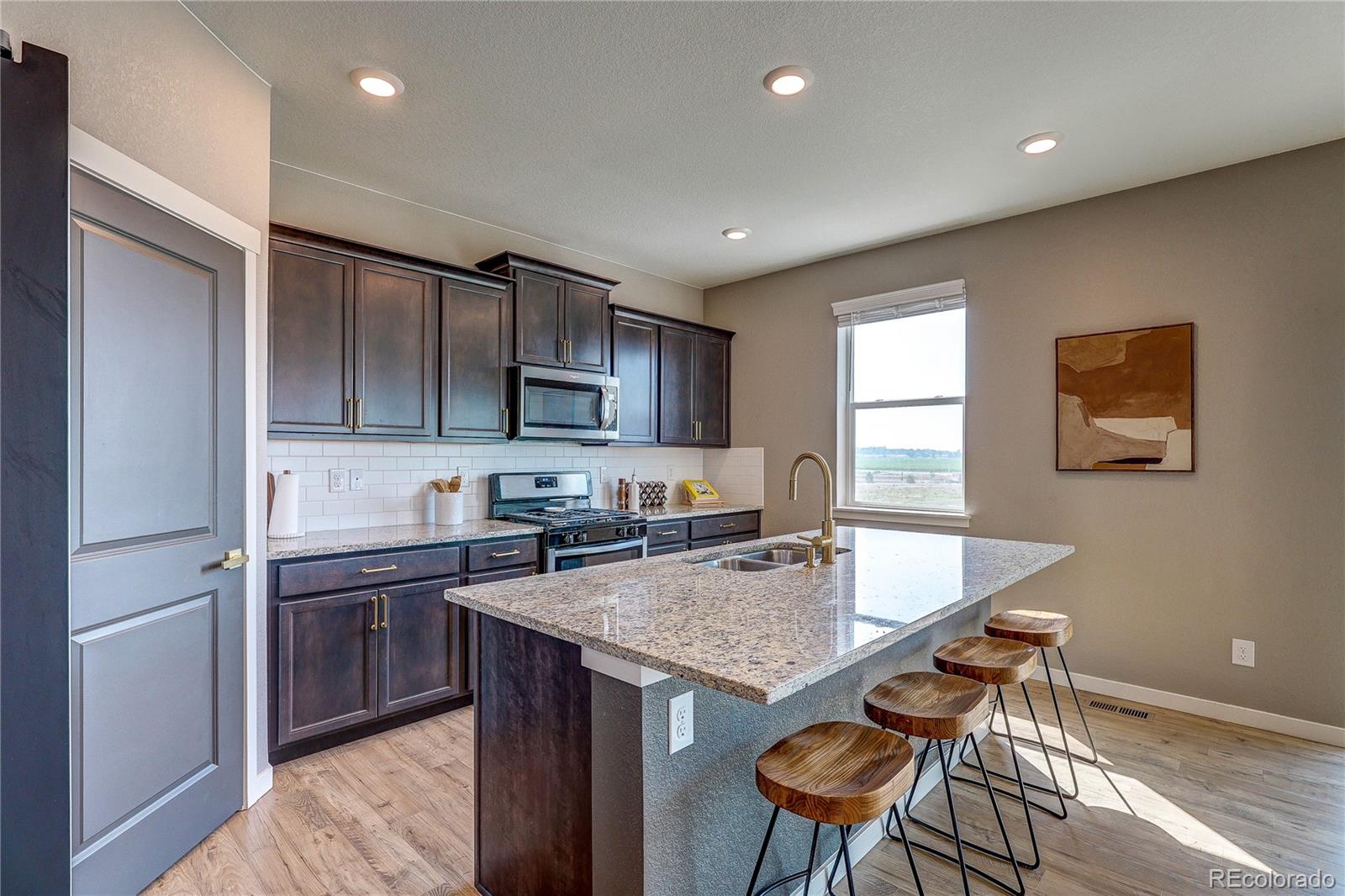 1335 Copeland Falls Road Severance, CO 80550 - Photo 12 of 48 a kitchen with granite countertop kitchen island stainless steel appliances a sink a stove a refrigerator cabinets and a window