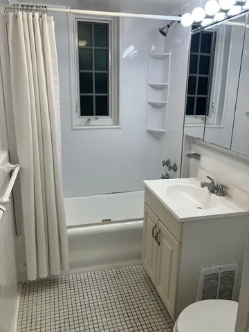 a bathroom with a sink a toilet a shower and a window