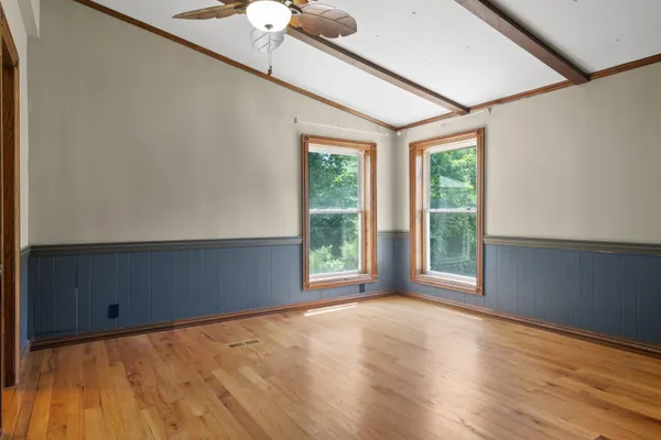 a view of an empty room with wooden floor and a window