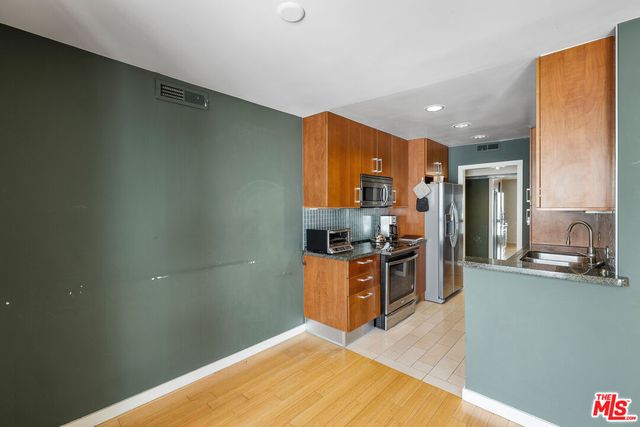 a kitchen with granite countertop a sink cabinets and stainless steel appliances