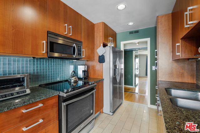 a kitchen with stainless steel appliances granite countertop a stove microwave and refrigerator