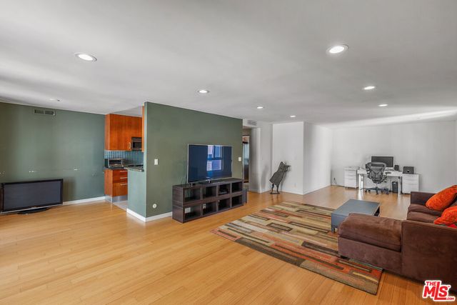 a living room with furniture a flat screen tv and kitchen view