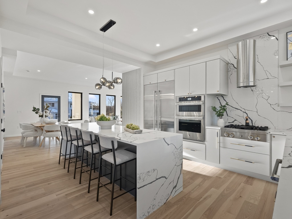 225 Walnut Street Saugus, MA 01906 - Photo 14 of 42 a kitchen with stainless steel appliances kitchen island granite countertop a table chairs stove and white cabinets